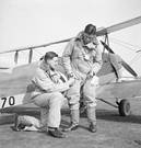Instructor and pupil in front of a de Havilland Tiger Moth at No. 7 EFTS, Desford. Both wear 1930 Pattern flying suits.