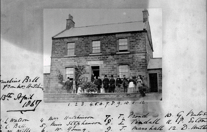 A group of people standing outside a brick house

Description automatically generated