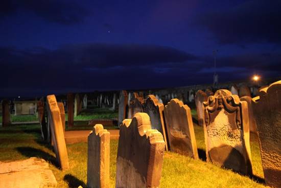 A cemetery at night with dark clouds

Description automatically generated