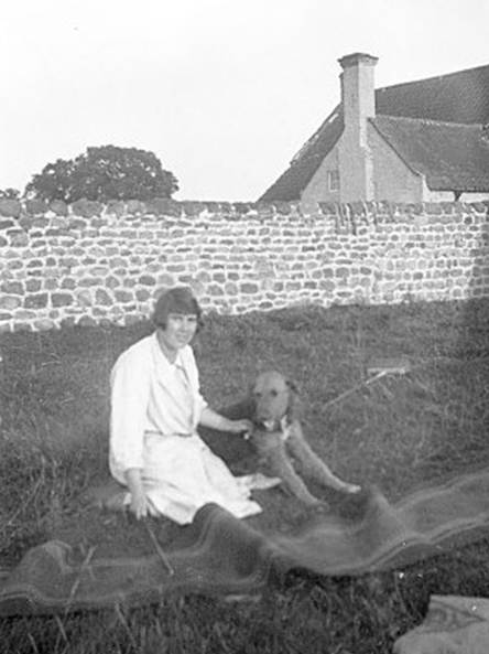 A person sitting on grass with a dog
Description automatically generated