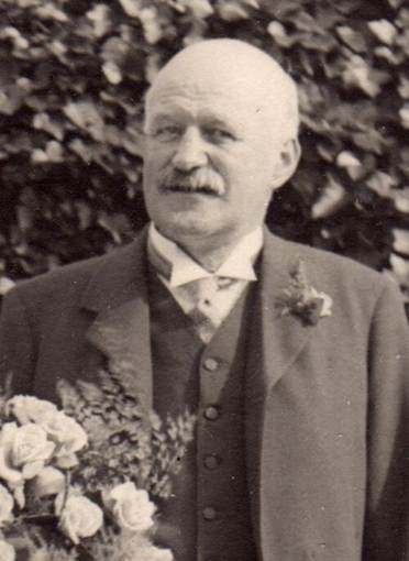 A person in a suit with flowers
Description automatically generated
