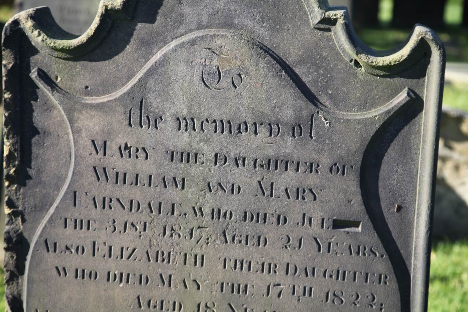 Close-up of a tombstone with engraved text

Description automatically generated