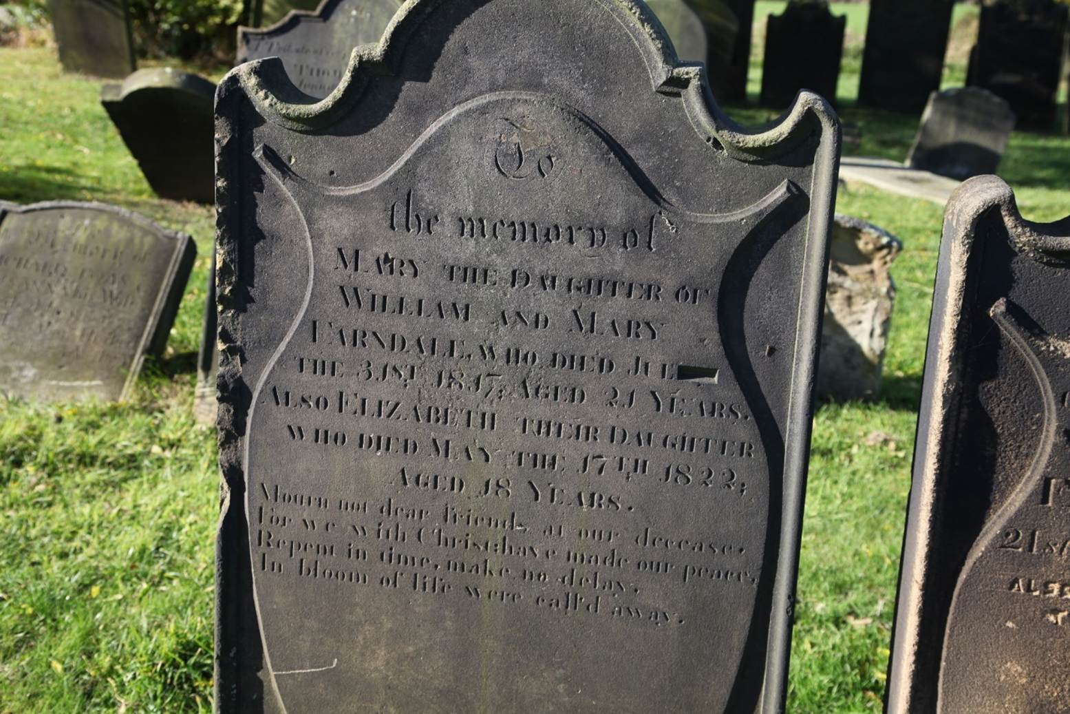A tombstone in a cemetery
Description automatically generated