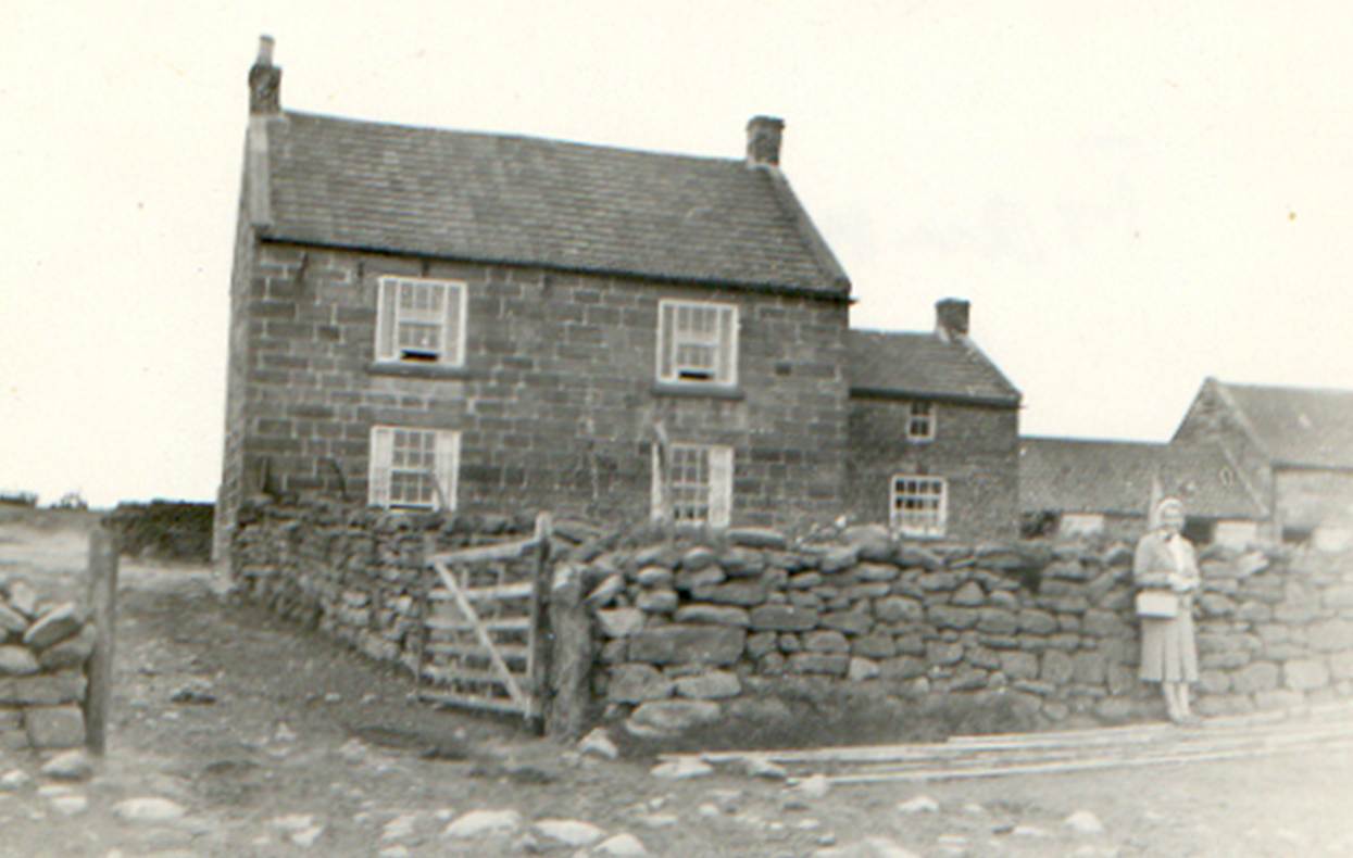 A couple of people standing in front of a stone house
Description automatically generated