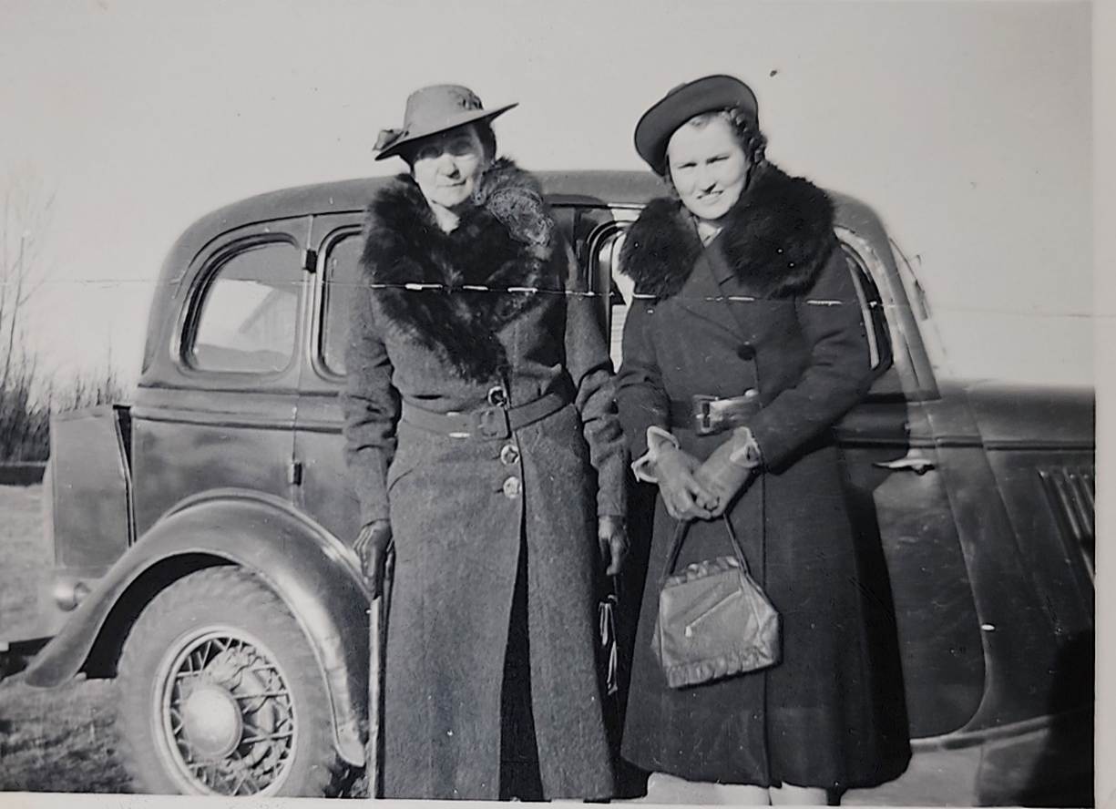 A couple of women standing next to a car
Description automatically generated