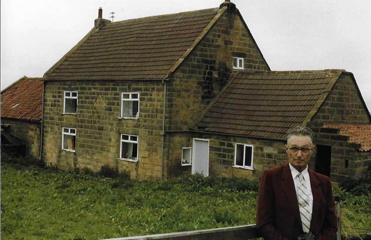 An old brick building with grass in front of a house
Description automatically generated