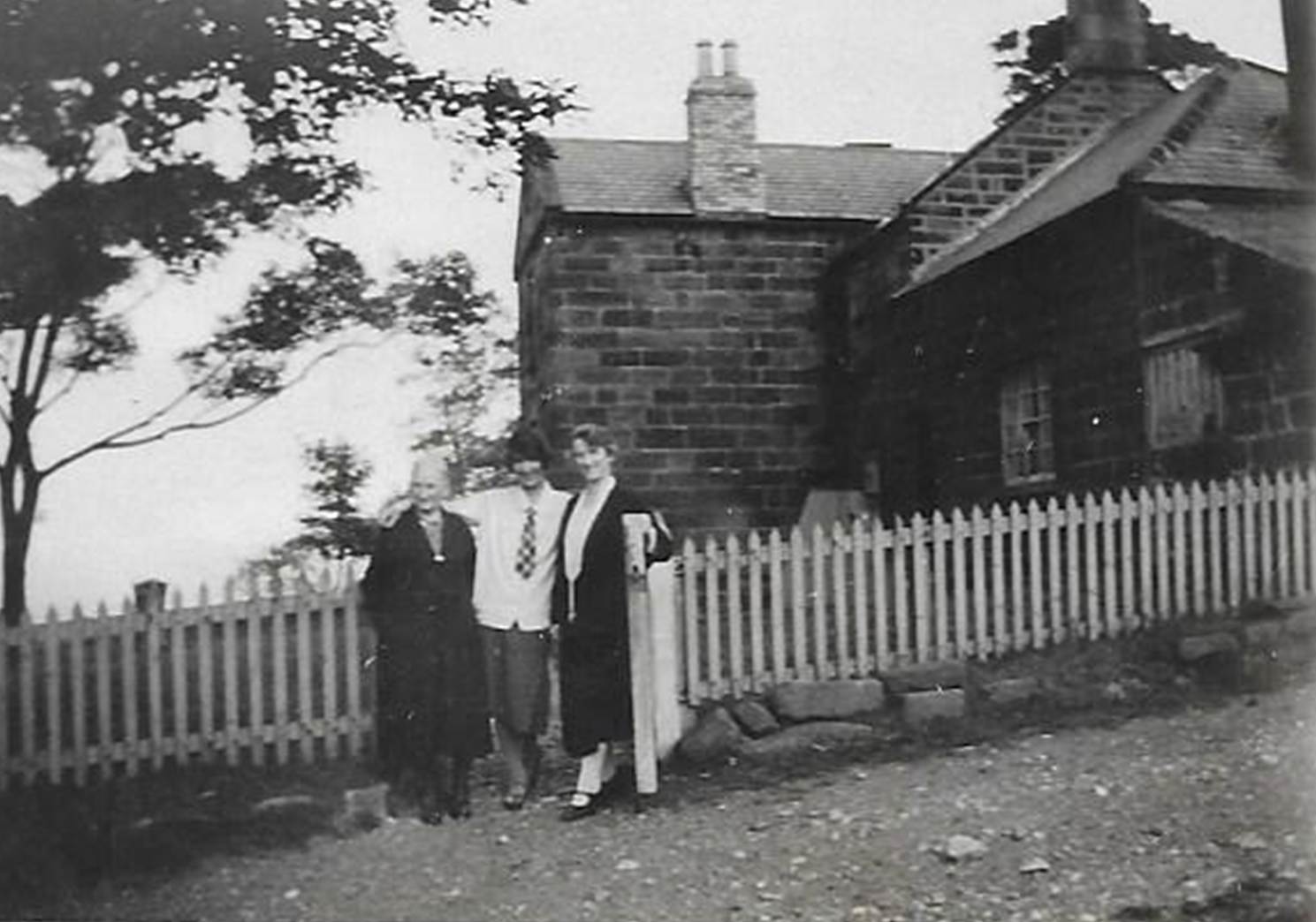 A black and white photo of a person walking by a fence
Description automatically generated