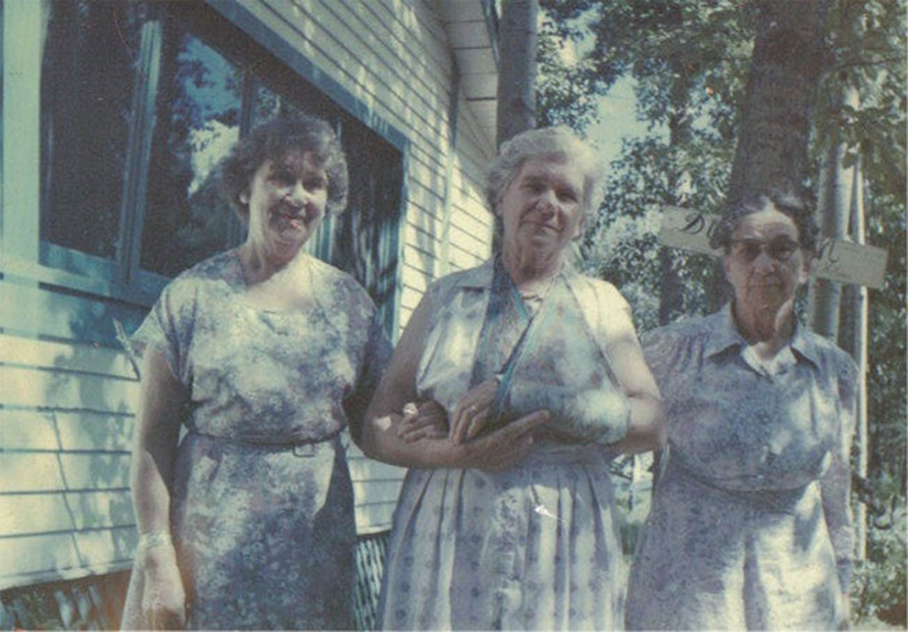 A group of women standing outside a house
Description automatically generated