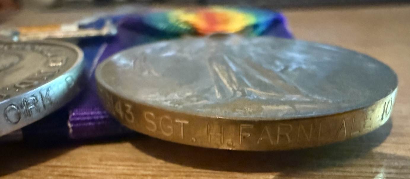A silver coin with a rainbow ribbon
Description automatically generated