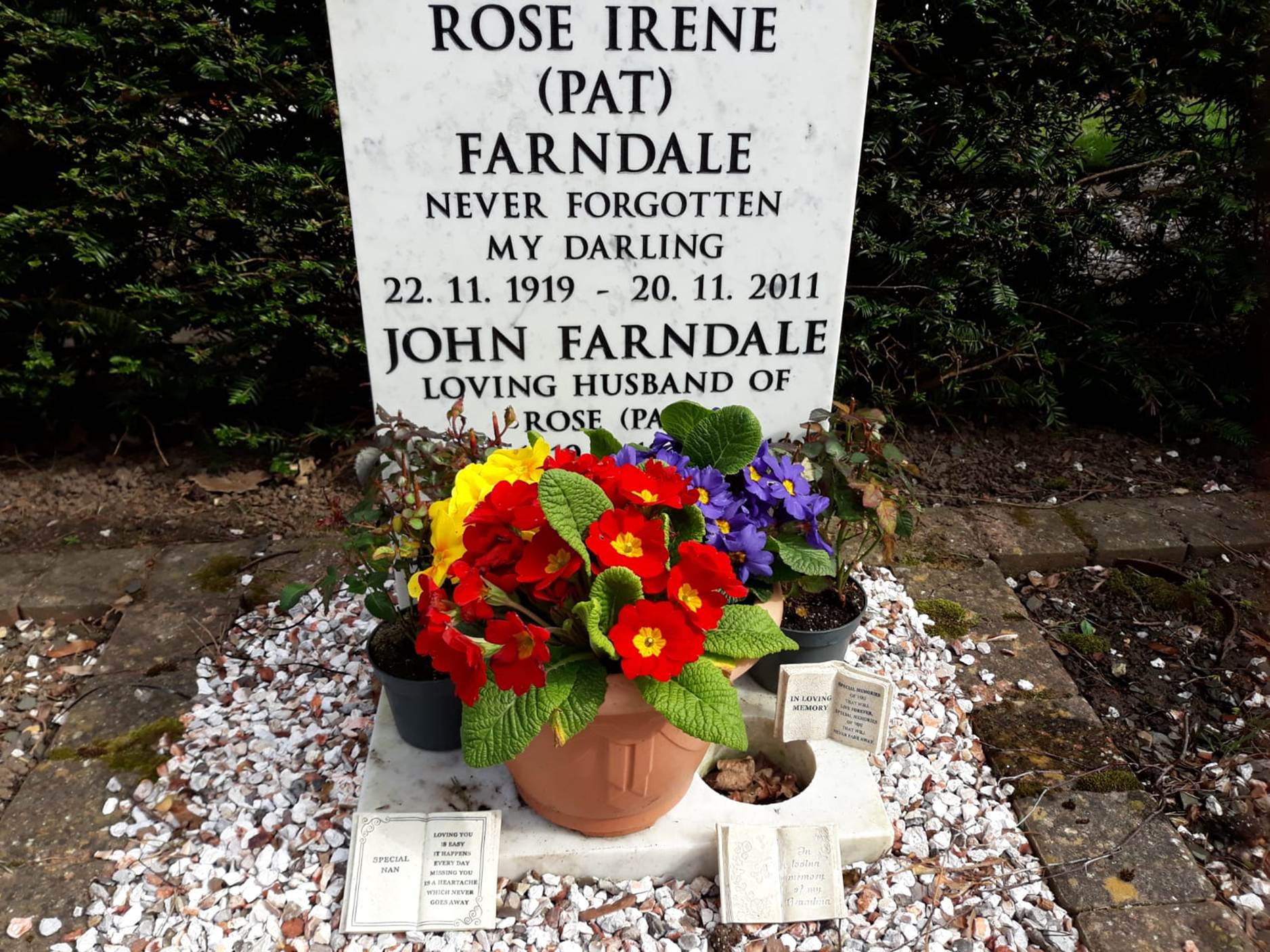 A grave stone with flowers in it
Description automatically generated