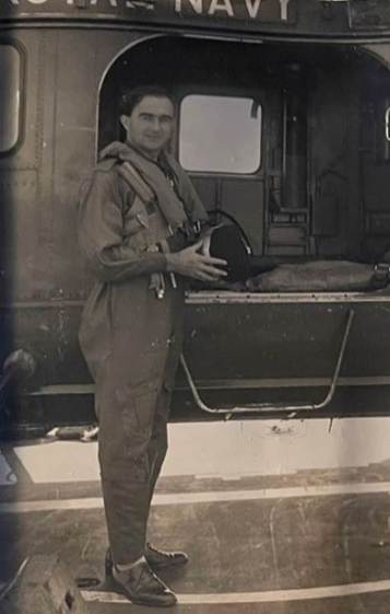 A person in flight suit standing next to a plane
Description automatically generated