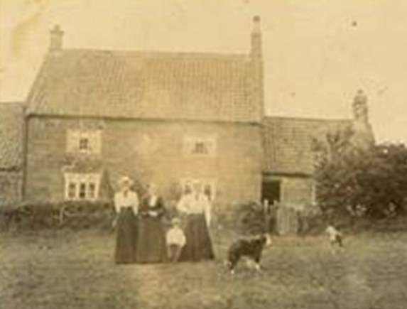 A group of people standing in front of a house
Description automatically generated