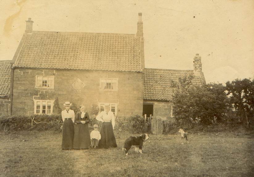 A family standing in front of a house
Description automatically generated