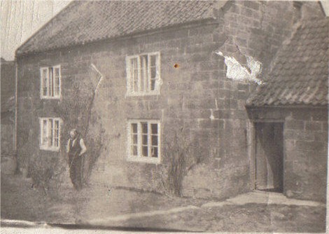 A person standing in front of a house
Description automatically generated