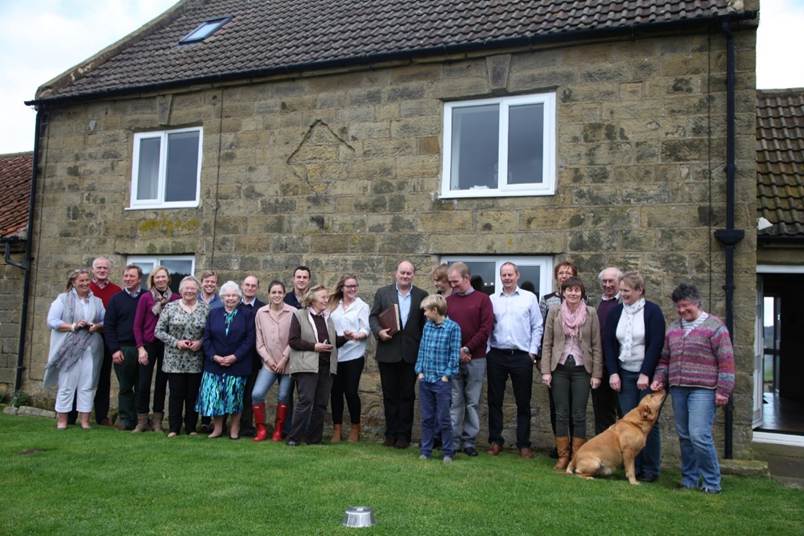 A group of people standing in front of a house
Description automatically generated