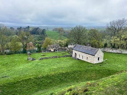 A stone building in a grassy field
Description automatically generated