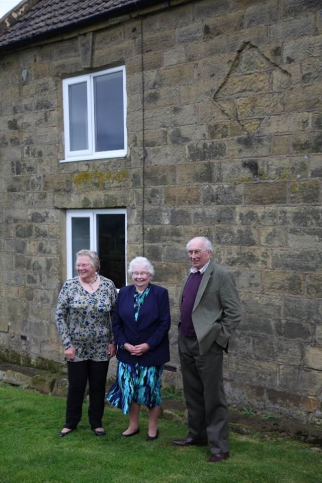 A group of people standing outside a brick building
Description automatically generated