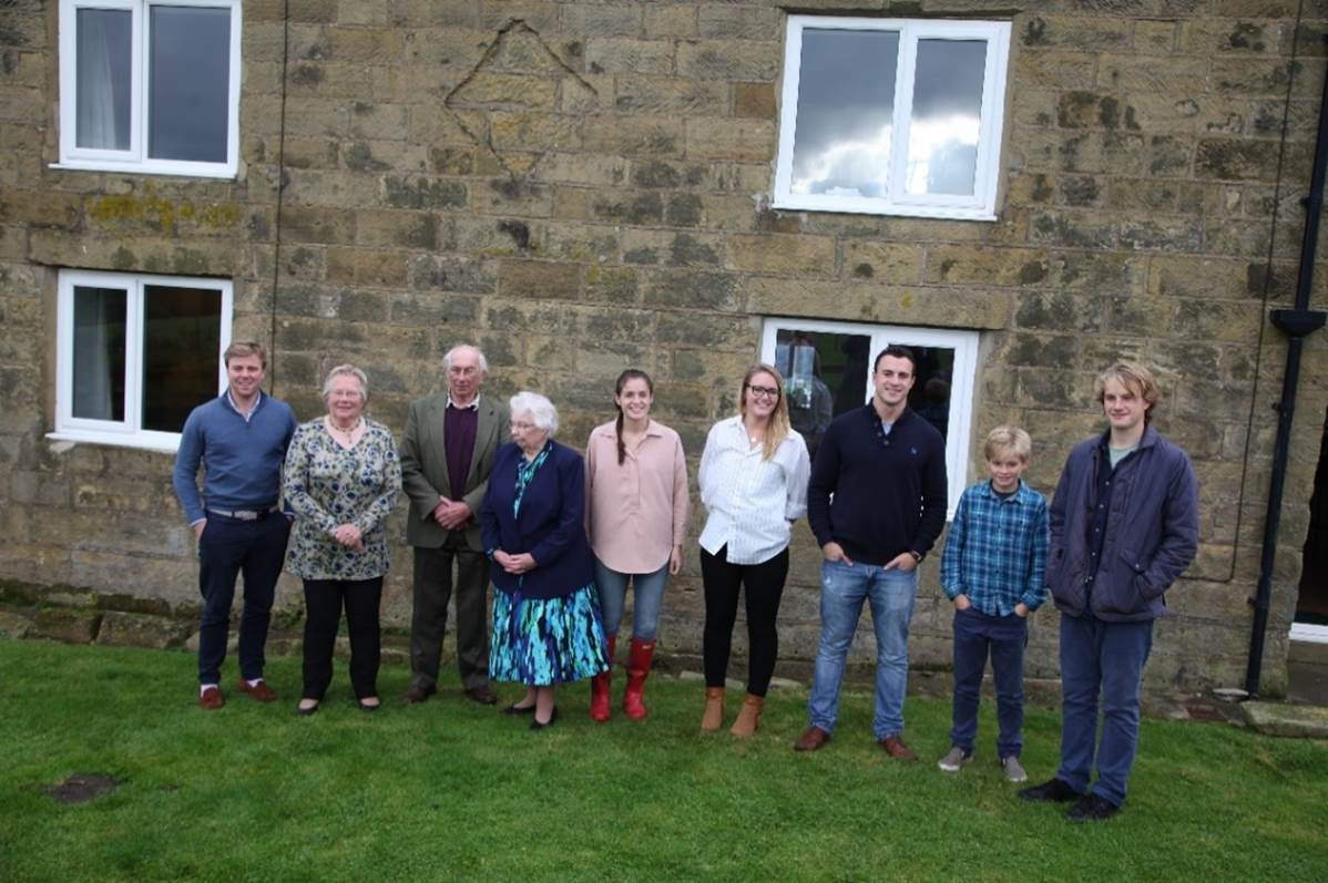 A group of people standing in front of a stone building
Description automatically generated