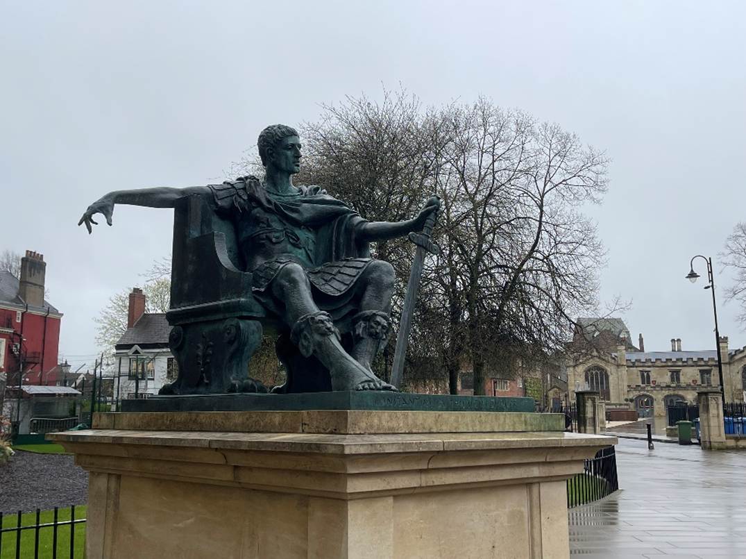 A statue of a person sitting on a bench
Description automatically generated