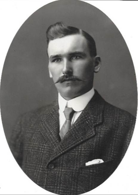 A vintage photo of a person in a suit and tie

Description automatically generated