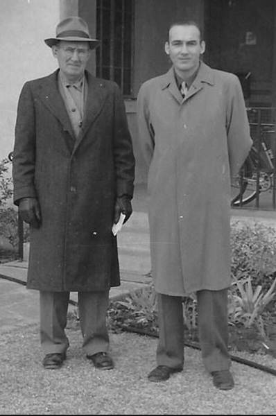 A couple of people standing in front of a fence
Description automatically generated