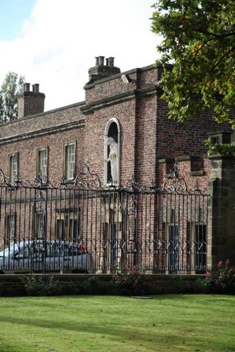 A brick building with a fence
Description automatically generated