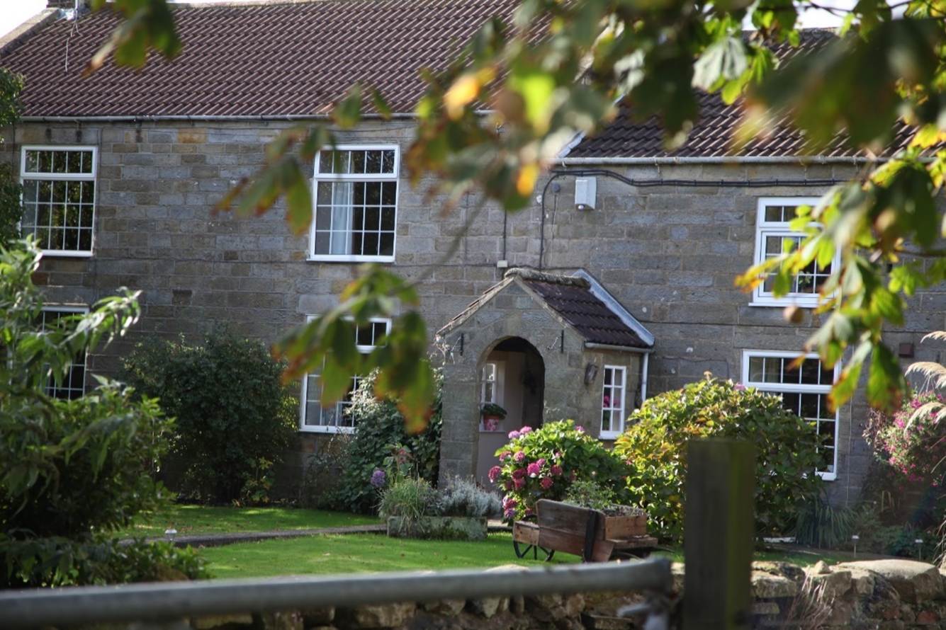 A stone building with a garden
Description automatically generated