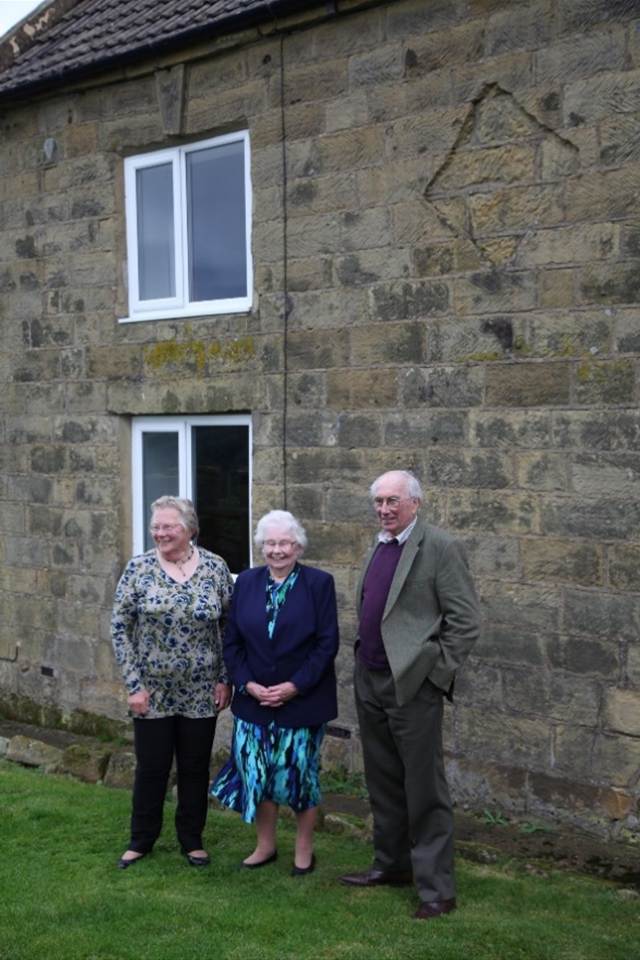 A group of people standing outside a brick building
Description automatically generated
