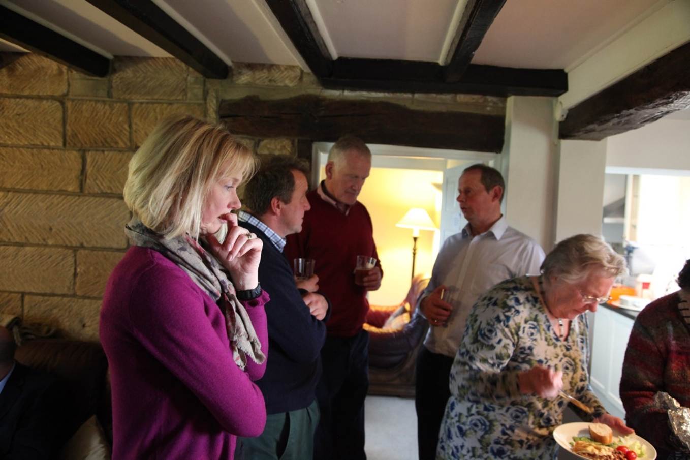 A group of people standing around a table
Description automatically generated