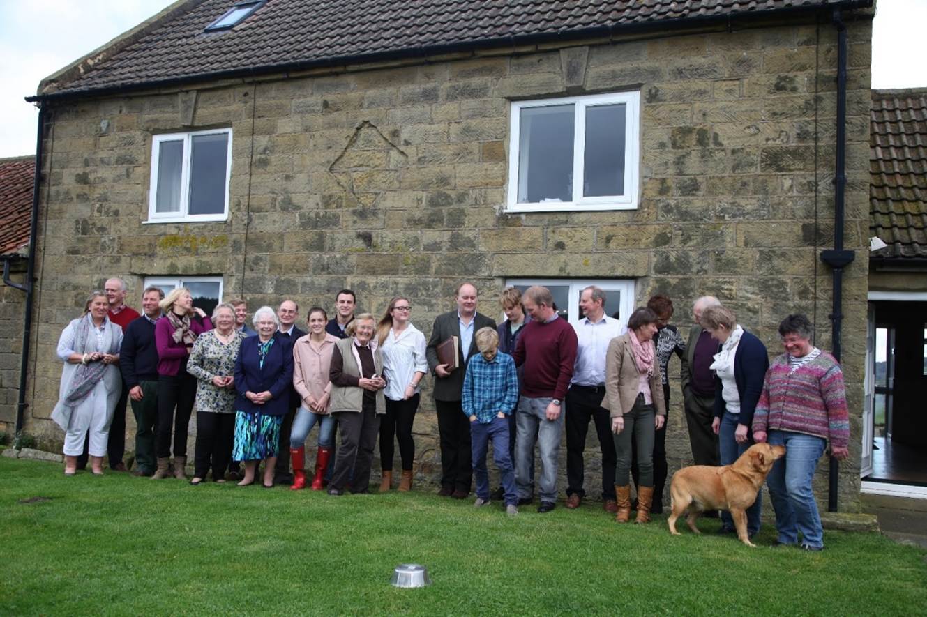 A group of people standing in front of a stone building
Description automatically generated