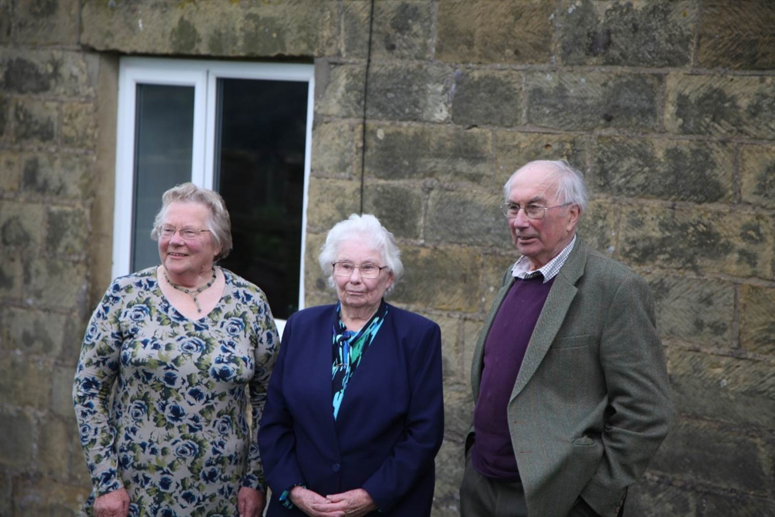 A group of old people standing outside a building
Description automatically generated