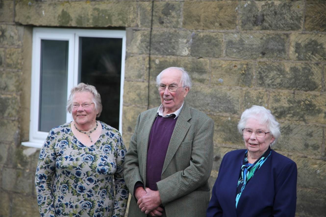 A group of old people standing outside a building
Description automatically generated